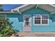 Up-close detail of a turquoise home with a classic white front door, complemented by lush greenery at 731 Cloverleaf Blvd, Deltona, FL 32725