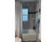 Bathroom with tub-shower combo, frosted glass window and tiled walls in neutral tones at 7407 Sw 202 Ct, Dunnellon, FL 34431