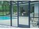 View of the pool and furniture inside the screened in enclosure through the glass door at 7407 Sw 202 Ct, Dunnellon, FL 34431