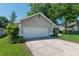 Two car attached garage in a single-story home featuring a well-manicured lawn and mature trees at 8120 Nw 48Th Ln, Ocala, FL 34482