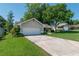 Two car attached garage in a single-story home featuring a well-manicured lawn and mature trees at 8120 Nw 48Th Ln, Ocala, FL 34482