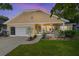 Dusk view of a charming home featuring a covered front porch, attached garage, and lush lawn at 9153 Sw 83Rd Ter # E, Ocala, FL 34481