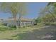 A view of the backyard showcasing a screened-in porch, lush lawn, and beautiful trees at 9325 Se 132Nd Pl, Summerfield, FL 34491