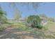 A beautifully landscaped backyard with mature trees, lush lawn, and a screened-in lanai at 9325 Se 132Nd Pl, Summerfield, FL 34491