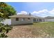 View of the backyard with a partial lawn, and a rear view of the single-story house with a neutral-colored exterior at 9896 Sw 56Th Ct, Ocala, FL 34476