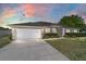 Beautiful single-story home featuring a well-manicured lawn, mature hedges, and an attached two-car garage under a colorful sky at 9896 Sw 56Th Ct, Ocala, FL 34476