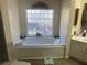 Bathroom features a large soaking tub with decorative tile and a block window for natural light at 9915 Sw 47Th Ave, Ocala, FL 34476