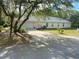 Spacious home with a paved driveway leading to an attached garage, surrounded by mature trees at 9915 Sw 47Th Ave, Ocala, FL 34476