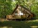 A-frame home with wooden accents and a cozy porch, nestled within a vibrant green and wooded landscape at 11420 Nw 110Th Ave, Reddick, FL 32686