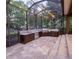 Outdoor kitchen with granite countertops, grill, and ample cabinet space in screened patio at 1450 Se 73Rd Pl, Ocala, FL 34480