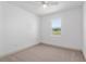 Empty bedroom with neutral carpet, ceiling fan, and a window with peaceful outdoor views at 1784 Nw 85Th Loop, Ocala, FL 34475