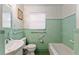 Bathroom featuring green tiling, a window, grab bars, a tub, a sink, and a toilet at 18027 Se 90Th St, Ocklawaha, FL 32179