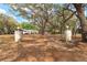 Long driveway leads to the home, framed by mature trees and stone pillars, showcasing the property's serene setting at 18027 Se 90Th St, Ocklawaha, FL 32179