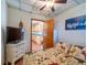Cozy bedroom featuring knotty-pine-style decor, a mounted flatscreen, and an open doorway to a bright kitchen at 23800 Ne 190Th St, Fort Mc Coy, FL 32134