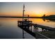 Picturesque sunset view of a tranquil lake with a private wooden dock and swing at 23800 Ne 190Th St, Fort Mc Coy, FL 32134