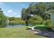 Picturesque backyard overlooking a tranquil lake, framed by mature trees and a well-maintained lawn, with stone table at 28 Gordon Ct, Leesburg, FL 34788