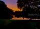 A tranquil lake view is visible through the trees during sunset at 28 Gordon Ct, Leesburg, FL 34788