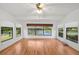 Serene sunroom with lake views from multiple windows, wood flooring, and a ceiling fan for relaxed comfort and scenic beauty at 28 Gordon Ct, Leesburg, FL 34788
