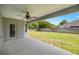A covered back porch with a ceiling fan overlooking the expansive green yard at 5144 Ne 9Th St, Ocala, FL 34470