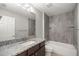 Well-lit bathroom with a granite countertop vanity and tiled shower-tub combination at 5144 Ne 9Th St, Ocala, FL 34470