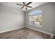 Bright bedroom featuring wood floors, a ceiling fan, and a large window with neighborhood views at 5144 Ne 9Th St, Ocala, FL 34470