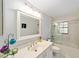Bright bathroom with a vanity, well-lit mirror, and a shower-tub combination enclosed by sliding glass doors at 5720 Se 22Nd Pl, Ocala, FL 34480