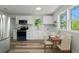 Well-lit kitchen with white cabinetry, stainless steel appliances, and a dining area by the windows at 6840 Sw 198Th Ave, Dunnellon, FL 34431