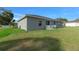 Back exterior showing a gray house with a bright green lawn and outdoor dining set at 7886 Sw 103Rd Loop, Ocala, FL 34476