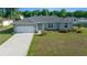 Charming single-story home features a manicured lawn, a two-car garage, and a light blue front door at 7886 Sw 103Rd Loop, Ocala, FL 34476