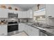 Bright kitchen featuring stainless steel appliances, granite countertops, and white cabinets at 7886 Sw 103Rd Loop, Ocala, FL 34476