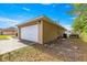 Exterior view of a detached garage with a white door and ample parking space at 8 Hemlock Radl, Ocala, FL 34472
