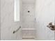 Walk-in shower with elegant marble tiling, seating and a hand rail at 8497 Sw 99Th Cir, Ocala, FL 34481