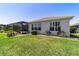 Backyard view features manicured lawn, screened-in patio, and exterior of the home with bright sunny skies at 9443 Sw 71St Loop, Ocala, FL 34481