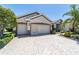 Lovely home with a large three-car garage, brick paver driveway, and verdant landscaping surrounding the property at 9443 Sw 71St Loop, Ocala, FL 34481