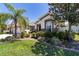 Well-manicured front yard with landscaped garden beds and a charming home exterior with a red front door at 9443 Sw 71St Loop, Ocala, FL 34481