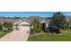 Elevated angle of a home with a paver driveway, three-car garage, and lush landscaping in a residential area at 9443 Sw 71St Loop, Ocala, FL 34481