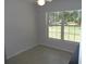 Sunny bedroom with tile floors and a large window showcasing the yard at 11653 Sw 72Nd Cir, Ocala, FL 34476