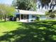 Charming home with a screened in porch, lush green grass, and a well-maintained yard at 12002 Sw 137Th Loop, Dunnellon, FL 34432