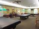 A billiard room with multiple tables covered with black table cloths under pendant lights and ceiling fans at 12002 Sw 137Th Loop, Dunnellon, FL 34432