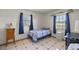 Bedroom with tile floors features a cozy bed, a small cabinet and 2 windows for natural light at 12351 Se Hwy 464, Ocklawaha, FL 32179