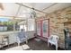 Relaxing screened patio features a ceiling fan, chair, and red French doors to the home at 12351 Se Hwy 464, Ocklawaha, FL 32179