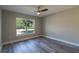 Sunlit bedroom offers a ceiling fan, wood-look floors and large window at 13588 Se 102Nd Ct, Belleview, FL 34420