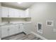 Well-lit laundry room with white cabinets, countertop, utility sink, and wood-look floors at 13588 Se 102Nd Ct, Belleview, FL 34420