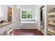 Well-lit bathroom with bathtub, wood floors, and view to walk-in closet and vanity at 16295 W Highway 40, Ocala, FL 34481