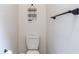 Minimalist bathroom featuring a white toilet, towel bar, and metal basket storage at 16295 W Highway 40, Ocala, FL 34481