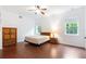 Bedroom with light walls, wood floors, ceiling fan, and a bright window with trees at 16295 W Highway 40, Ocala, FL 34481