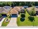 Aerial view of a home with an attached two car garage, a screened-in lanai, a green lawn, and lush landscaping at 16299 Sw 14Th Avenue Rd, Ocala, FL 34473