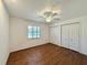 A bedroom with a ceiling fan, wood-look floors, and a large closet with white bi-fold doors at 1711 Sw 63Rd St Rd, Ocala, FL 34476