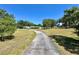 Long driveway leading to the house in a rural setting with trees and a vast lawn at 1711 Sw 63Rd St Rd, Ocala, FL 34476