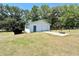 A white outbuilding with garage door is offset by basketball hoop and green lawn at 1711 Sw 63Rd St Rd, Ocala, FL 34476
